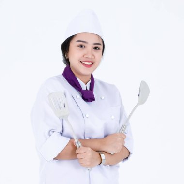 Asya profesyonel restoranının portre çekimi aşçı üniformalı kadın yönetici aşçı ayakta gülümsüyor kameraya bakın beyaz arka planda spatula yüzgeci çevirici.