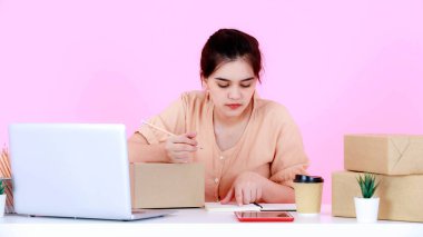 Asya 'nın mutlu ve başarılı genç bayan girişimci stüdyo fotoğrafı. Pembe arka planda çalışan iş kadını..