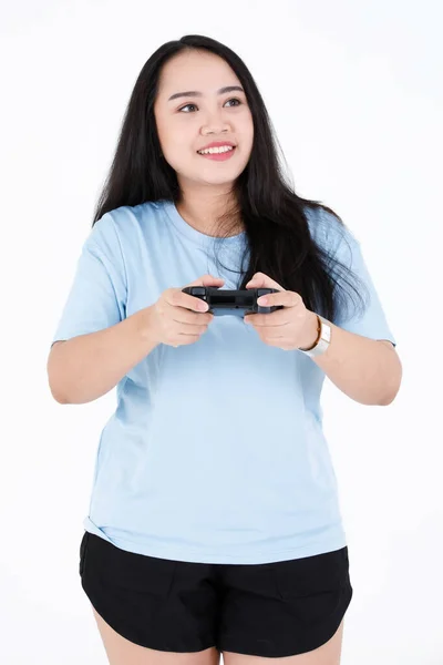 アジアのぽっちゃりぽっちゃり健康的な長い黒髪の女性ゲーマーモデルのポートレートスタジオショットで青カジュアルシャツ笑顔見てカメラを保持しています無線ジョイスティック再生ビデオコンソールゲーム上の白の背景 — ストック写真