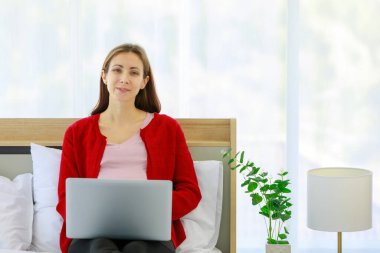 Beyaz, genç, sağlıklı, hamile, gündelik kıyafetli bir anne. Yatak odasında ceketli, koca göbeğin üstünde oturmuş dizüstü bilgisayarla komik komedi filmi seyrediyor..