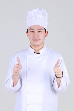 Zarif yemek pişirme üniforması giymiş deneyimli ve zeki Çinli şef. Gülümse ve kendine güvenerek mutfakta dur. Lüks yemek pişirme konusunda uzman olarak.