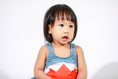 Beyaz arka planda oturan şirin gri köpek balığı kostümlü Asyalı küçük kız bebek modelinin stüdyo fotoğrafı.