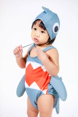 Beyaz arka planda duran şirin gri köpek balığı kostümlü Asyalı kız bebek modelinin stüdyo fotoğrafı.