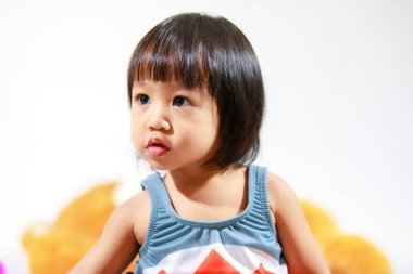 Renkli plastik toplar ve beyaz arka planda yüzük oyuncakları ile yerde oturan şirin gri köpek balığı kostümlü Asyalı küçük kız bebek modelinin stüdyo fotoğrafı.