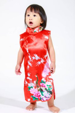 Asya 'da küçük şirin, masum, anaokulu anaokulu kızı kız çocuk kırmızı Çin geleneksel Qipao Cheongsam kıyafetiyle kısa siyah saç modeli beyaz arka planda tek başına duruyor..