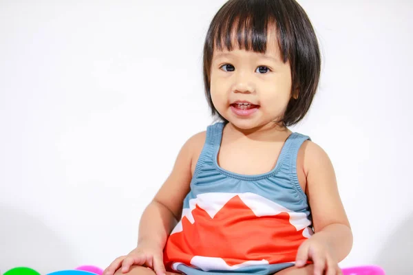 身着可爱的灰色鲨鱼装束泳衣的亚洲女婴小女儿坐在地板上 背景是五彩斑斓的塑料球和环状玩具的工作室照片 — 图库照片