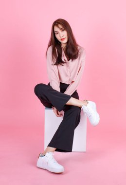 Asyalı genç ve güzel hippi kadın modelin sıradan bir sokakta çekilmiş portresi. Spor ayakkabı ve güneş gözlüğü takıyor. Kameraya gülümsüyor..