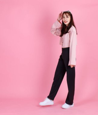 Asyalı, genç, güzel, hippi bir genç kızın günlük uzun kollu gömlek giydiği ve güneş gözlüklü pembe arka planda gülümseyen bir fotoğraf stüdyosu fotoğrafı..