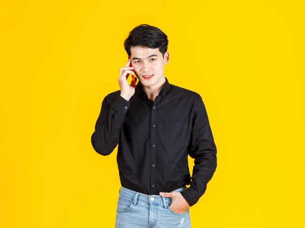 스튜디오는 노란색 배경에 스마트폰을 청바지와 셔츠를 아시아 사업가 사진을 찍었다 — 스톡 사진