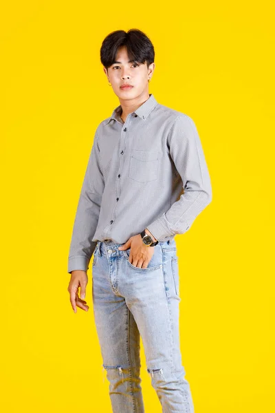 黄色の背景に立ってスタイリッシュなファッショナブルなカジュアルな服装で千年のアジアの若い男性ファッションモデルのスタジオショット — ストック写真