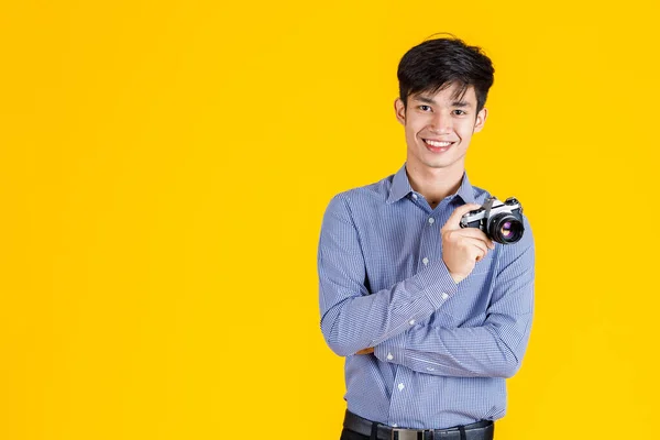 黄色の背景にデジタル一眼レフミラーレスカメラを目指して開催笑みを浮かべて立ってカジュアルな服装で千年のアジアのプロの男性ファッション写真家ジャーナリストのポートレートクローズアップスタジオショット — ストック写真