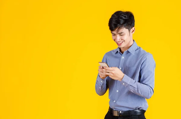 千年の肖像画スタジオショットアジアのプロの成功した男性ビジネスマンの従業員の公式衣装に立って笑顔を保持スマートフォンは黄色の背景に仮想ビデオゲームをプレイ — ストック写真