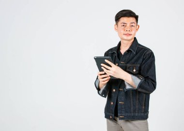 Portre stüdyosu Asyalı genç, kendine güvenen yakışıklı kısa saçlı, sıradan bir kot ceket giyen, elinde tablet bilgisayarla gri arka planda kameraya bakan hippi erkek modelini çekti..
