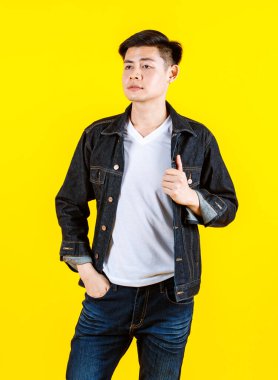 Portre stüdyosu, sıradan bir kot pantolon giyen Asyalı yakışıklı erkek hippi mankeni sarı arka planda poz veren kameraya bakarken çekti..