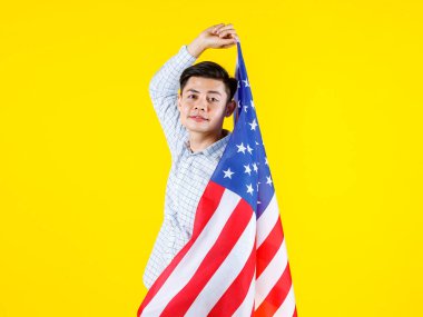 Milenyum Asyalı genç yakışıklı erkek iş adamı modelinin portre çekimi. Günlük kıyafet içinde. Büyük Amerika Birleşik Devletleri bayrakları sarı arka planda..
