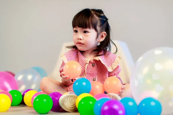 小可爱幼稚园小女孩身穿红色长裙 独自坐在地板上 与色彩斑斓的氦气气球在灰色背景下嬉戏的肖像工作室镜头 — 图库照片