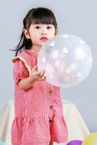 小可爱幼稚园小女孩身穿红色长裙 独自站在地板上 与色彩斑斓的氦气气球在灰色背景下嬉戏的肖像工作室镜头 — 图库照片