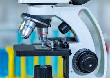 Büyüteç yakınlaştırıcı mercek mikroskop kamerasının yakın çekim görüntüleri hastane laboratuvarındaki çalışma masasının üzerine yerleştirilmiş cam teçhizat test tüpü rafı Erlenmeyer cep şişesi ve bilgisayar monitörü..