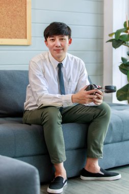 Asyalı, düşünceli, yakışıklı, profesyonel, başarılı, iş adamı resmi iş kıyafetiyle rahat koltukta oturuyor..