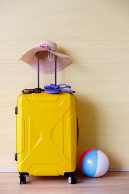 Sarı bavul, el işi şapka, terlik, sarı arka planda top yaz seyahati konsepti..