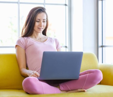 Milenyum Kafkasyalı genç, mutlu, sağlıklı, koca göbekli hamile anne rahat koltukta oturmuş dizüstü bilgisayarla kocasıyla internetten sohbet ediyor..