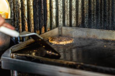 Tereyağlı taze pişmiş hamburgerin yakın plan çekimi, margarinli kıymalı kıyma ve domuz pastırması kirli, sağlıksız yerel restoran tezgahında tavada ızgara..