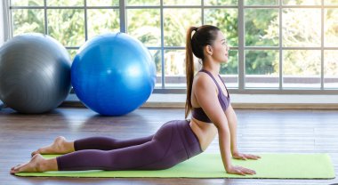 Milenyum Asyalı genç, sağlıklı, sağlıklı, güçlü, seksi kadın spor modelleri gündelik spor kıyafetleri içinde sırt üstü uzanmış pilates sınıfındaki yoga minderinde köpek pozu veriyorlar..