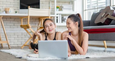 İki bin yıllık Asyalı genç, sağlıklı, sağlıklı, güçlü, seksi, spor modelleri gündelik ürünler giyip halı döşemesine uzanmış, dizüstü bilgisayardan yoga pilates dersi öğreniyorlar..