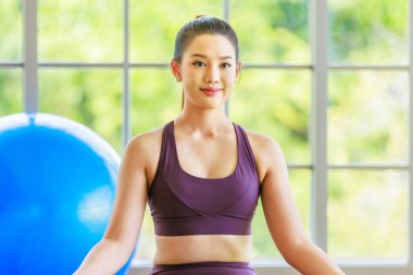 İki bin yıllık Asya 'lı genç, sağlıklı, ince, güzel, seksi spor modelleri gündelik ürünler giyip Lotus pozisyonunda bacak bacak üstüne atarak yoga minderinde egzersiz topuyla oturuyorlar..