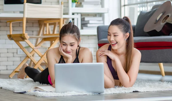 İki bin yıllık Asyalı genç, sağlıklı, sağlıklı, güçlü, seksi, spor modelleri gündelik ürünler giyip halı döşemesine uzanmış, dizüstü bilgisayardan yoga pilates dersi öğreniyorlar..