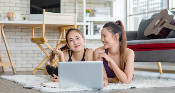 İki bin yıllık Asyalı genç, sağlıklı, sağlıklı, güçlü, seksi, spor modelleri gündelik ürünler giyip halı döşemesine uzanmış, dizüstü bilgisayardan yoga pilates dersi öğreniyorlar..