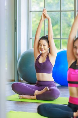 İki bin yıllık Asyalı genç, sağlıklı, sağlıklı, güçlü, seksi, spor modelleri gündelik ürünler giyip bacak bacak bacak üstüne atarak pilates salonunda yoga minderinde yan yana oturuyorlar..