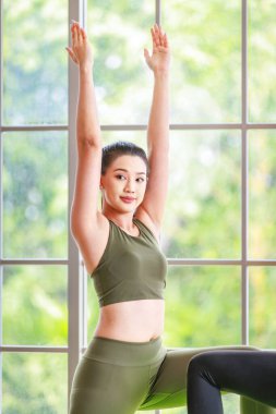 Milenyum Asya 'lı genç, sağlıklı, sağlıklı, güçlü, seksi, spor modelleri, günlük ürünler, spor kıyafetleri içinde gülümseyerek yoga minderinde Malasana pozu veriyorlar. Pilates sınıfı stüdyosunda.