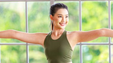 Milenyum Asyalı genç, sağlıklı, güzel, sağlıklı, güçlü, seksi, spor model, spor kıyafetleri içinde spor topunun üzerine oturmuş, kollarını sallayarak spor salonunda kaslarını açarak ışık efekti yapıyor..