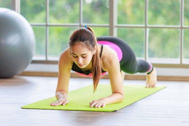 Asyalı, genç, sağlıklı, güzel, seksi, spor modelleri gündelik spor kıyafetleri içinde, ısınıyor, kollarını uzatıyor, yoga minderinde ayak parmaklarına dokunuyor, egzersiz topuyla derste..