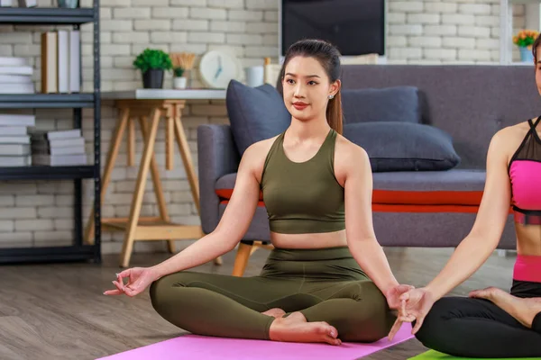 İki bin yıllık Asya 'lı genç, sağlıklı, ince, güzel, seksi spor modelleri gündelik ürünler giyip Lotus pozisyonunda bacak bacak üstüne atarak yoga minderinde egzersiz topuyla oturuyorlar..