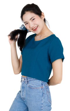 Asyalı güzel, dost canlısı, at kuyruğu saçlı, rahat gömlekli ve kot pantolonlu, el ele tutuşmuş, beyaz arka planda gülümseyen bir kadın modelin portresi..