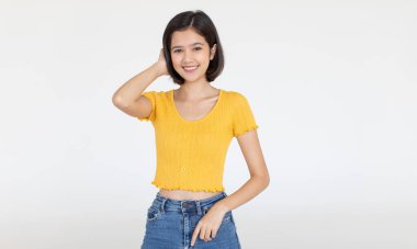 Asyalı, arkadaş canlısı, kısa saçlı bir genç kızın, sıradan bir bluz ve kot pantolonla beyaz arka planda el ele tutuşup gülümserken çekilmiş bir portresi..