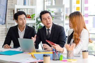 Group of cheerful Asian millennial professional successful male businessman and female businesswoman in formal suit sitting smiling holding fists up together celebrating customer agreement deal done.