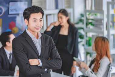 Portre, Asyalı mutlu, neşeli, zeki, kendine güvenen, bin yıllık profesyonel, başarılı, spor ceketli, iş adamı şirket toplantı odasında sırıtan kollarını kavuşturmuş bir vaziyette çekti..