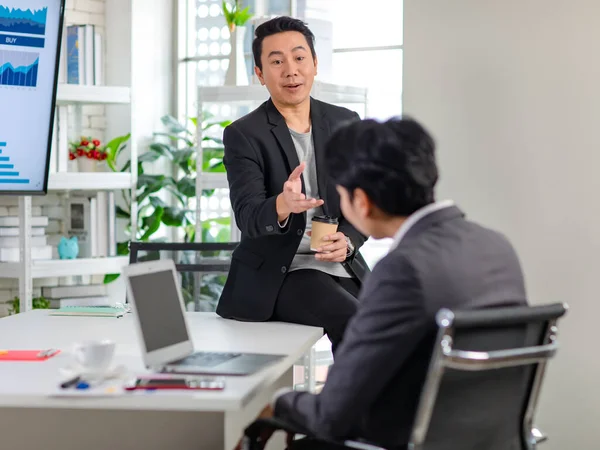 Asyalı, profesyonel, başarılı, sıradan takım elbiseli bir erkek işadamı kahve molası verir. Ofisteki tanınmayan iş arkadaşıyla konuşur..