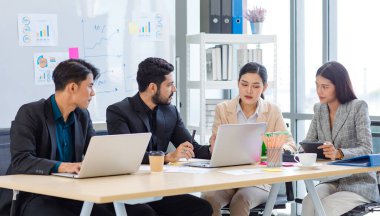 Group of millennial Asian Indian multinational multicultural male and female businessman businesswoman teamwork in formal suit sitting smiling brainstorming meeting together in office conference room.