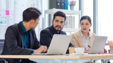 Group of millennial Asian Indian multinational multicultural male and female businessman businesswoman teamwork in formal suit sitting smiling brainstorming meeting together in office conference room.