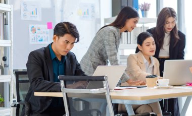 Group of millennial Asian Indian multinational multicultural male and female businessman businesswoman teamwork in formal suit sitting smiling brainstorming meeting together in office conference room.