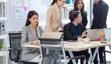 Closeup shot of millennial Asian professional successful beautiful female businesswoman secretary in formal suit sitting smiling typing working with laptop notebook computer on table in meeting room.