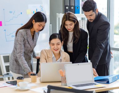 Multicultural multinational millennial Asian female businesswomen Indian male businessman boss in formal suit helping working brainstorming together with laptop computer in conference meeting room.