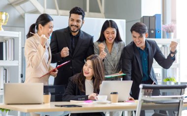 Multicultural multinational millennial Asian female businesswomen Indian male businessman boss in formal suit helping working brainstorming together with laptop computer in conference meeting room.