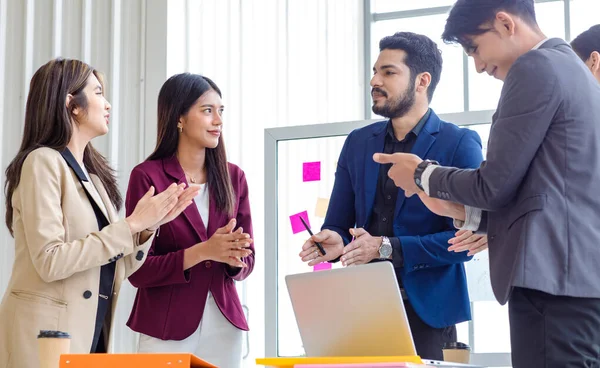 Millennial Indian Asian professional successful male female businessman businesswoman group in formal suit discussing brainstorming sharing business solution ideas in company conference meeting room.