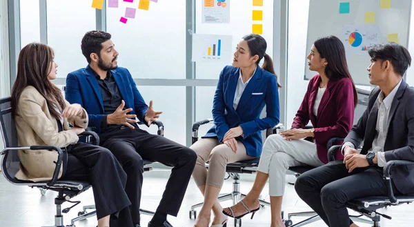 Millennial Indian Asian professional successful male female businessman businesswoman group in formal suit sitting together discussing brainstorming sharing business solution ideas in meeting room.