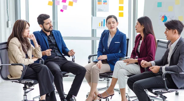 Millennial Indian Asian professional successful male female businessman businesswoman group in formal suit sitting together discussing brainstorming sharing business solution ideas in meeting room.